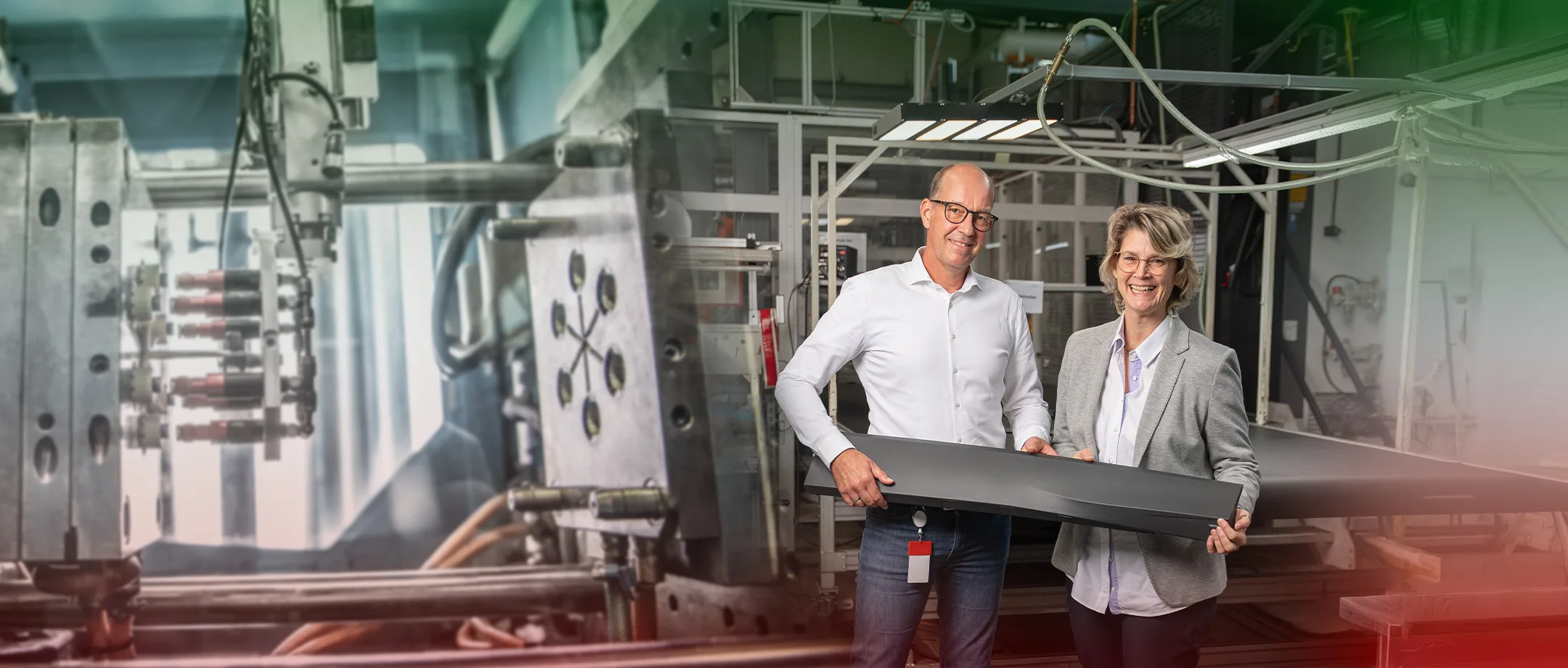 Zwei Mitarbeitende mit einem Kunststoff-Großbauteil in der Fertigung